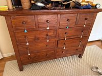 Front view showing multiple drawers with wooden knobs and visible scratches on the wood surface.