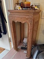 Square wood side table showing front and side carved details with natural wood grain.