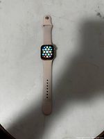 Full front view of Apple Watch SE showing app grid on screen with pink silicone strap.