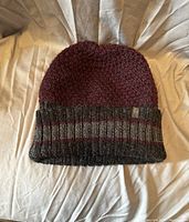 Front view of the knit alpaca wool hat showing the burgundy color and striped cuff.