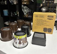 Photo shows 8 furniture risers, 4 brown and 4 black, with a box describing main features.