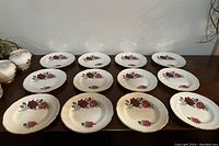 12 Royal Imperial fine china plates displayed in rows showcasing the floral pattern and gold trim.