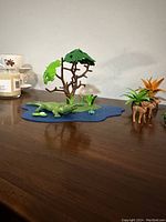Tabletop view of the Playmobil alligator habitat setup including blue water base, tree, alligator, baby alligator, plants, and deer with fern plant.