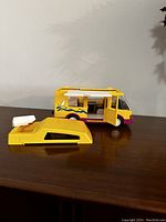 Yellow and purple camper motorhome with roof removed showing interior and side door open