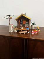 View of entire Playmobil Sportsman Cabin set including cabin, rocky base with tree and owl, picnic table, canoe with figurine and animals positioned around.