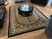 Top-down view of the large Turkish area rug in a living room setting showing the full rug beneath a round glass coffee table and brown leather sofa.