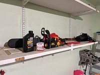 Shelf with all items including chainsaw, motor oil, bug zapper, and brushes.