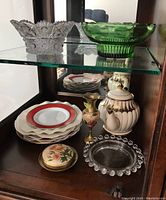 Glass and china items including clear cut glass bowl with scalloped edge, green ribbed glass bowl, teapot with brown stripes, stack of decorative plates, brass floral trinket box and small dish with matching floral bud vase
