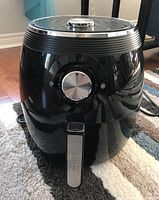 Front and full view of the black Dash Deluxe Air Fryer showing the dial timer and handle.