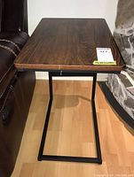 Side view of one end table showing dark wood rectangular top and black steel frame base