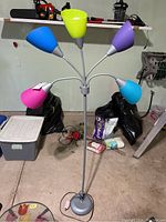 Front view of metal floor lamp with five adjustable arms and colored plastic shades in a garage setting.