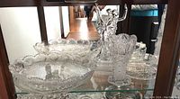 Display of clear cut glass trays, bowls, and ballerina figure on shelf