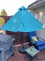 Full view of turquoise half patio umbrella on deck with black metal stand, showing the overall appearance and size.