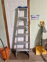Front view of the Reynolds 6 ft. aluminum folding ladder, showing full height and plastic tray on top with visible damage.