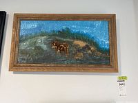 Frontal photo of the framed painting depicting a lone caribou in a landscape under a blue sky.