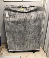 Photo of the rollaway bed folded and covered with a grey protective fabric cover, showing its compact storage state.