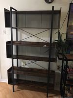 Front view of the wood and steel frame display shelf showing three wooden shelves and enclosed compartments at the top corners.