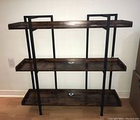 Front view of three-level wood and steel frame bookcase, showing dark wood shelves with raised edges and black metal supports.
