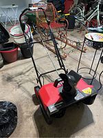 Full image of the Benchmark snow thrower in a garage setting showing the overall condition and design.