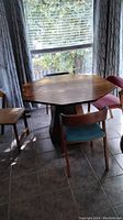 Photo of octagonal faux wood table with four chairs of different colored vinyl seats and backs.