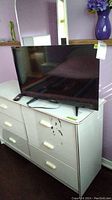 Westinghouse 32 inch flat-screen TV on white dresser with remote beside it