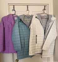 Three lightweight fall/winter coats hanging on hooks showing different colors and styles.