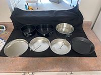 Full view of all baking dishes including pie plates, springform cake pans and metal baking pan arranged on table with black cloth background