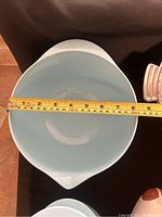 Top view of a blue hard plastic mixing bowl with a diameter of approximately 7.5 inches shown against black background with measuring tape for scale.