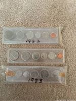 Coins in plastic holders arranged by year: 1983, 1984, 1985 with all denominations visible.