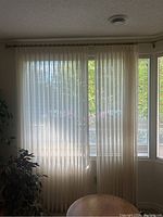 Full view of sheer curtains hung on brass curtain rod spanning multiple windows, showing natural light filtering through.