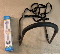 Photo of Aquasense grab bar in original box and bed safety handle with straps laid on floor.