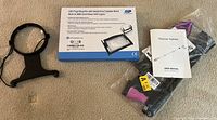 LED page magnifier with stand box and new reacher grabber with user manual on carpet floor.