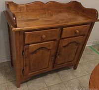 Front angled view of wooden cabinet showing drawers and doors