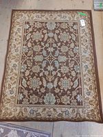 Full view of the rectangular wool area rug with brown base color and floral design.