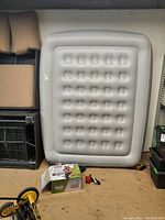 Photo of the inflated Coleman queen size air bed upright against a shelving unit showing the inflation and shape including surface indentation pattern.