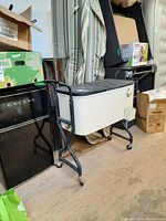 Photo of the white cooler with black lid on black metal stand, showing the overall shape and condition.