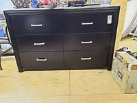 Front view of dark wood dresser showing six drawers with silver handles and glass top