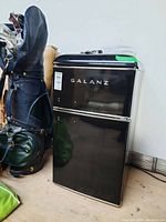 Closed front view of the Galanz mini fridge with visible brand logo and black finish.