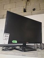 Front view of LG 23.5 inch monitor displaying its screen and stand with a power cable on surface.