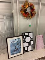 Framed print and black multi-photo plastic frame next to a wall