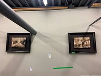 Two sepia toned landscape prints in dark wood float frames hanging on wall near ceiling.