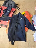 Neosport wetsuit folded with two life jackets visible on a wood floor