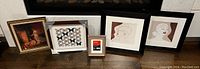 Overview of all five framed artworks arranged on the floor showing variety and framing styles.