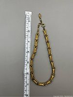 Gold-tone vintage necklace with unique bamboo-style links shown next to ruler for scale approximately 7.5 inches long