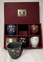 Set of five ceramic tea cups featuring cherry blossom motif in original red box with Japanese labels