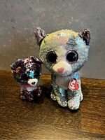 Front view of both sequenced TY kitten plush toys on a wood surface showing their sequin details and TY tags.