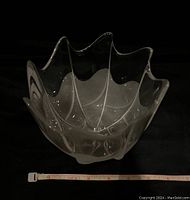Clear Rosenthal glass bowl with a frosted base and sculpted wavy peak rim shown with measuring tape for size reference on black background.