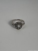 Top view showing pear-shaped central crystal, surrounding small crystals, and detailed band design.