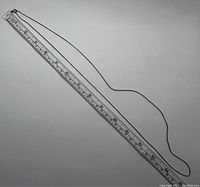 Full length of the silver chain necklace placed next to a ruler for size reference, approximately 21 inches long.