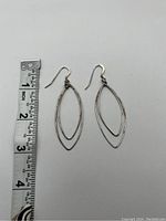 Front view of pair of double oval sterling silver dangle earrings alongside ruler showing length about 2.75 inches